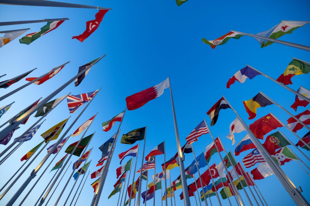 pexels-photo-14676984-14676984 International flags waving against a clear blue sky in Doha, Qatar, symbolizing unity and diversity.