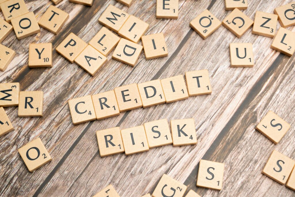pexels-photo-19867471-19867471 Scattered wooden letter tiles spelling 'credit risk' on a rustic wooden surface.